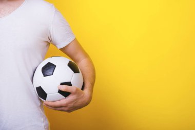 Bir futbol topu tutan yakışıklı adam fotoğrafı, ayakta ovr sarı arka plan 