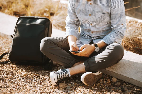 Hipster adam şehirde oturan ve cep telefonu kullanarak