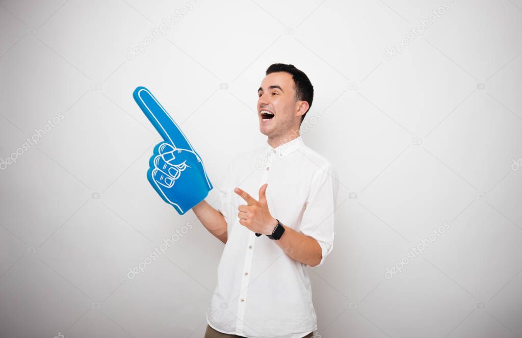 Handsome young guy, wearing a big finger glove, and pointing away over isolated background