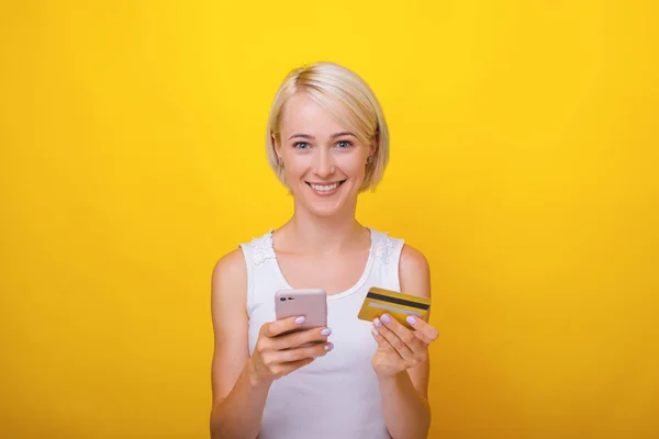 Photo of a blonde woman, using mobile phone and credit card, whi — Stock Photo, Image