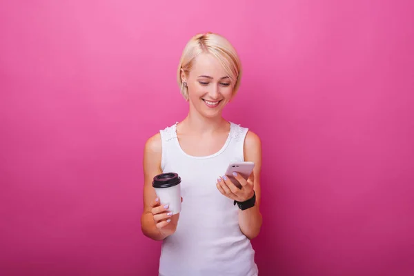 Mulher alegre, usando telefone celular e uma xícara com café, standi — Fotografia de Stock