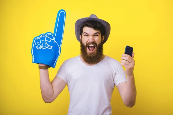 Photo of excited bearded guy with big fan glove, and mobile phon
