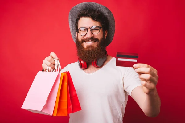 Shopaholic homem, segurando alguns sacos, e mostrando cartão de crédito em ca — Fotografia de Stock