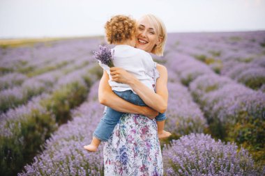 Mutlu genç anne oğlunu kucaklıyor ve alan ortasında Lavanta bir buket tutan.