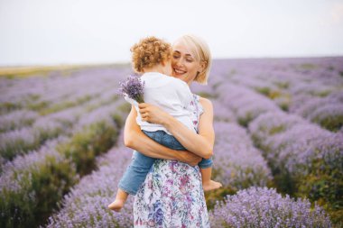 Neşeli Genç Anne Çocuk, Lavanta bir buket ve lavanta alanının ortasında gülümseyen tutar.