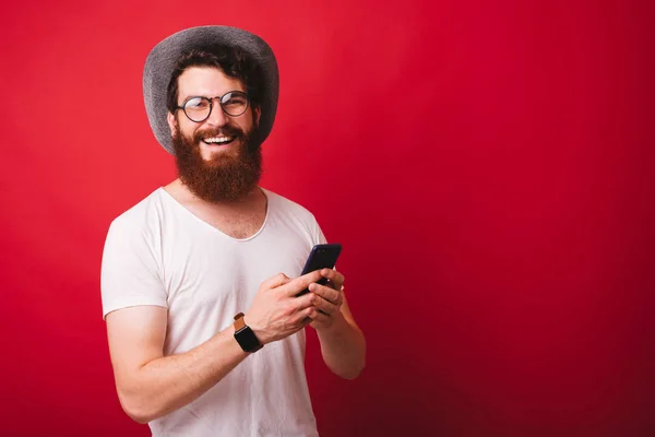 Photo of smiling young hipster man holding smartphone and lookin — Stock Photo, Image