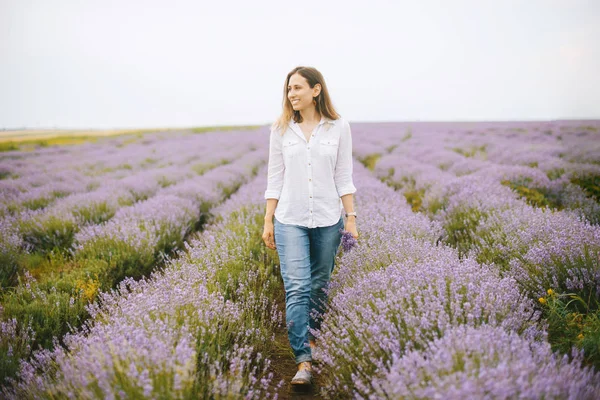 Una joven alegre camina en medio del campo de lavanda . — Foto de Stock