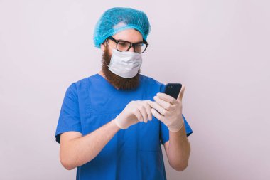 Onun Smartphone kullanarak maske ile doktor cerrah fotoğrafı 