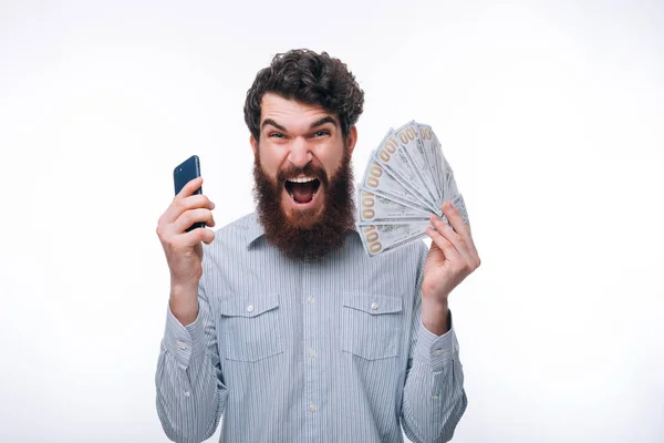 Photo of amazed bearded man in casual holding smartphone and cas — Stock Photo, Image
