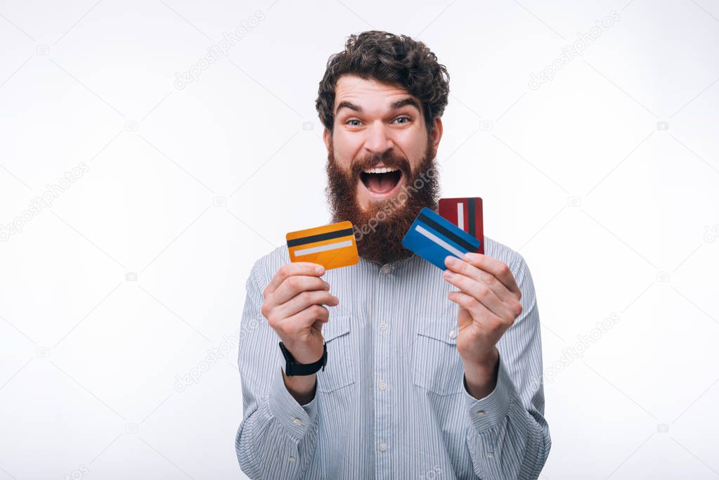 Photo of amazed man in casual holding different colorful credit 