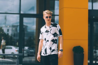 Genç yakışıklı trendy adam giyen güneş gözlüğü ve bakarak 