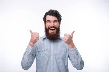 Rahat gülümseyen ve gösteren başparmak sakal ile hayran adam