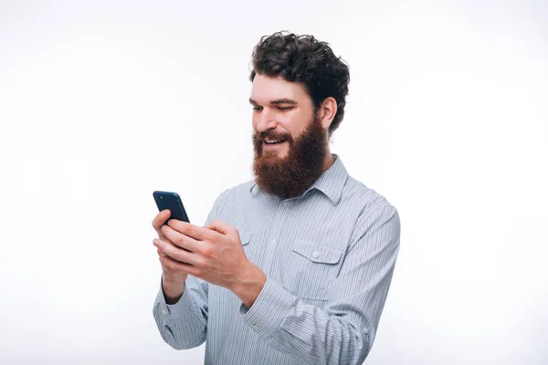 Jeune homme barbu hipster souriant dans casul en utilisant son téléphone sur — Photo