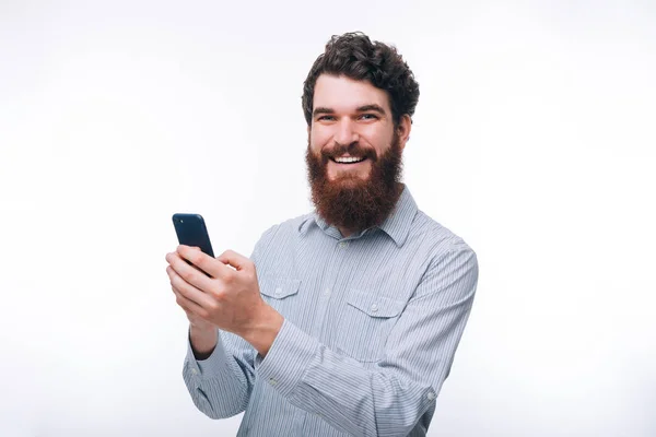 Photo of handsome cheerful young man with beard holding smartpho — Stock Photo, Image