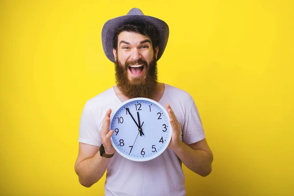 Retrato de un joven sonriente sosteniendo un gran reloj blanco mientras st — Foto de Stock