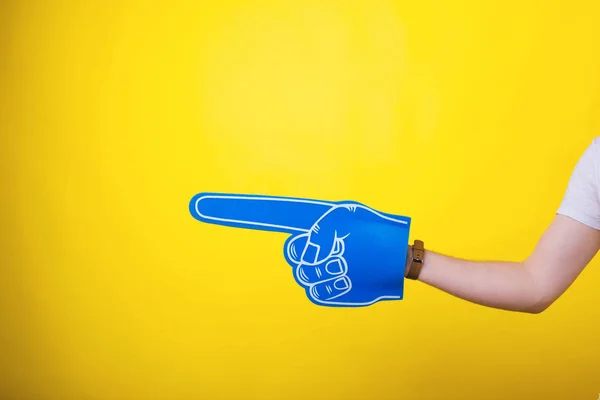 Fan finger foam pointing at copyspace over yellow background
