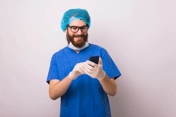 Ritratto di medico allegro guardando il suo smartphone — Foto Stock