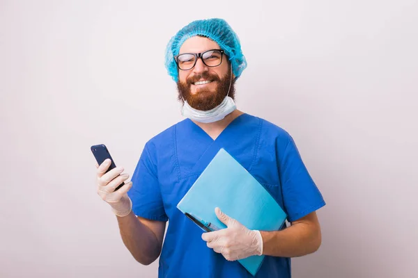 Ritratto di chirurgo sorridente che tiene smartphone e lavoro di carta — Foto Stock