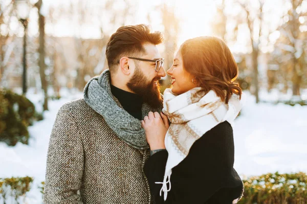 Potrait eines Paares, das einen Winterspaziergang macht, sich bei Sonnenuntergang umarmt. — Stockfoto