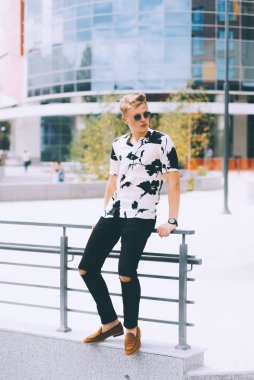 Genç ciddi adam oturuyor ve dışarıda ofis yakınında bakıyor.