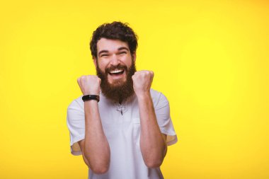 Her iki eli yukarı mutlu sakallı adam o çıktı ve sarı duvara yakın bir kazanan gösteriyor