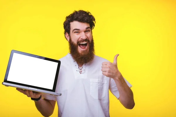 Photo de jeune homme étonné tenant un ordinateur portable avec écran blanc et montrant pouce vers le haut — Photo