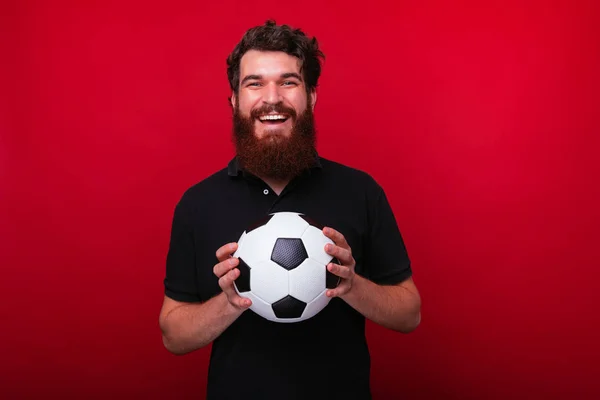 Foto de torcedor barbudo, segurando uma bola de futebol enquanto olha — Fotografia de Stock