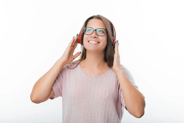 Ritratto di giovane donna felice che ascolta la sua musica preferita con le cuffie mentre sta in piedi su sfondo bianco — Foto Stock