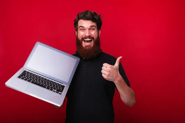 Aufgeregter bärtiger Typ in schwarzem T-Shirt, mit Laptop und Show — Stockfoto