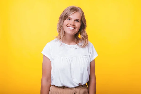 Retrato de una joven sonriente y alegre mujer de pie sobre un fondo amarillo — Foto de Stock