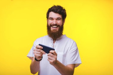 Neşeli sakallı adam oynarken veya kameraya gülümseyerek bakarken telefonuna mesaj atıyor.