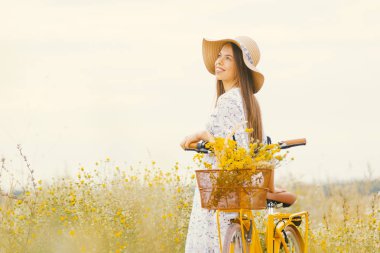 Zarif uzun saçlı bayan onu vintage bisiklet yanında bir alanda sıcaklık zevk.