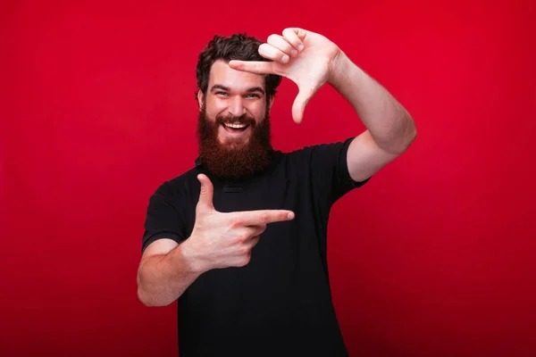 Foto de un hombre alegre con barba que enmarca la imagen con las manos — Foto de Stock