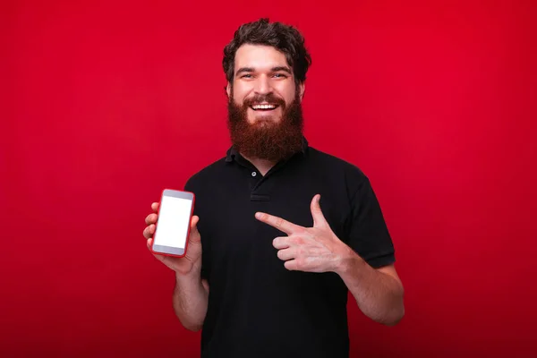 Foto de un joven encantador con barba apuntando a la pantalla del teléfono inteligente —  Fotos de Stock