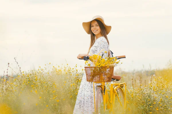 Młoda Elegancka dama ubrana w strój i letni kapelusz stojący w pobliżu jej roweru patrzy na kamerę. — Zdjęcie stockowe