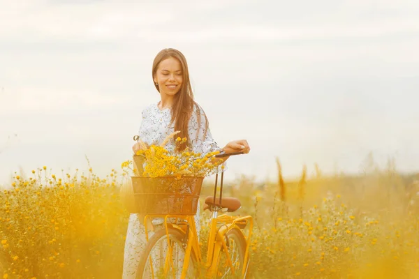Spokojny młody uśmiechnięta dziewczyna trzyma jej żółty rower na łące. — Zdjęcie stockowe