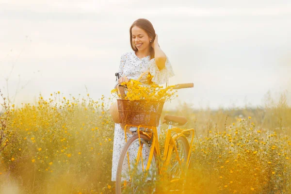 Wesoły młody piękny kobieta chodzenie z jej rower w a żółty łąka. — Zdjęcie stockowe