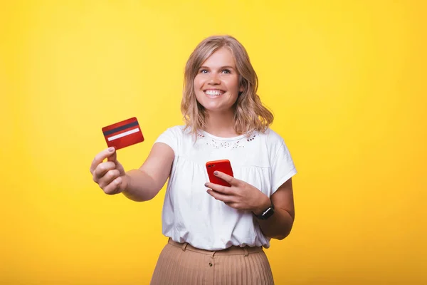 Neşeli genç kadının kredi kartını gösteren ve akıllı telefonu tutan fotoğrafı — Stok fotoğraf