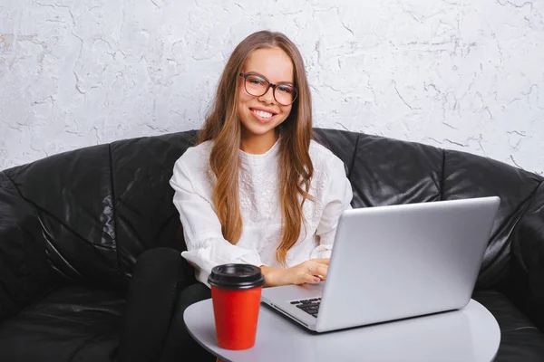 Foto von glücklichen jungen Frau mit Laptop und wotking mit Tasse von — Stockfoto