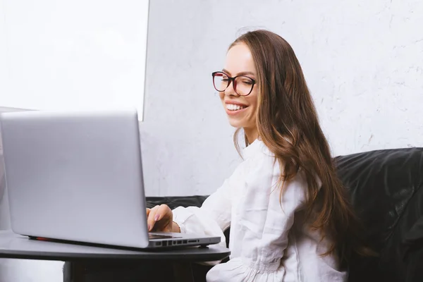 Фото улыбающейся женщины, работающей на ноутбуке в офисе — стоковое фото
