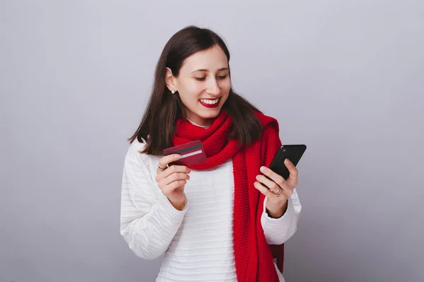 Photo of young smiling woman looking at smartphone and holding c — Stock Photo, Image