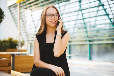 Genç bayan telefonda konuşuyor ve terace, moda kibir oturuyor