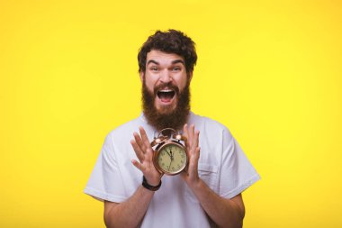 Heyecanlı sakallı adam bir vintage saat tutan, yello üzerinde duran