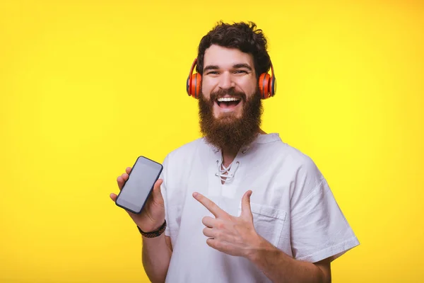 Foto de hombre alegre apuntando a su teléfono inteligente y usando hea —  Fotos de Stock