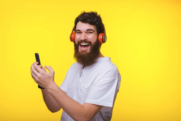 Ritratto di giovane sorridente con barba che tiene il telefono e liste — Foto Stock