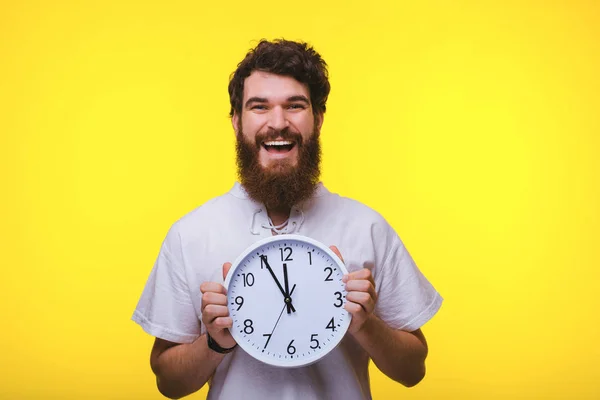 Φωτογραφία του άντρα με γένια κρατώντας ένα ρολόι, στέκεται πάνω από το κίτρινο πίσω — Φωτογραφία Αρχείου