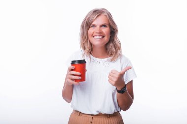 Neşeli sarışın genç kadın, kahve ile fincan tutan ve başparmak gösteren