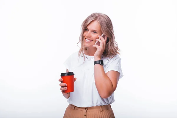 Uma jovem loira, falando ao telefone enquanto segura uma xícara com — Fotografia de Stock