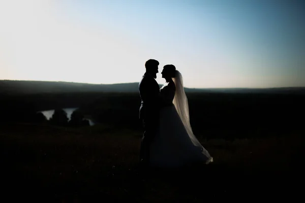 Photo of silhouette, bride and groom in eveningon top fo the hil — Stock Photo, Image