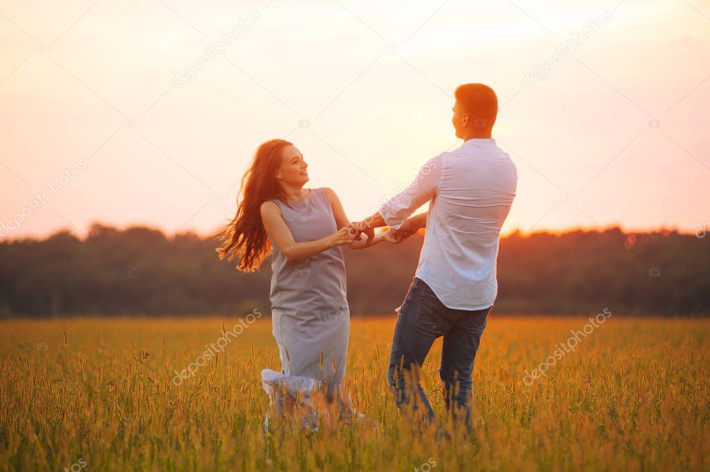 Photo of couple dancing in a file on sunset, having fun